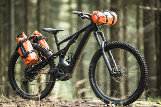 Mountain bike with orange aeroe dry bags in a forest setting