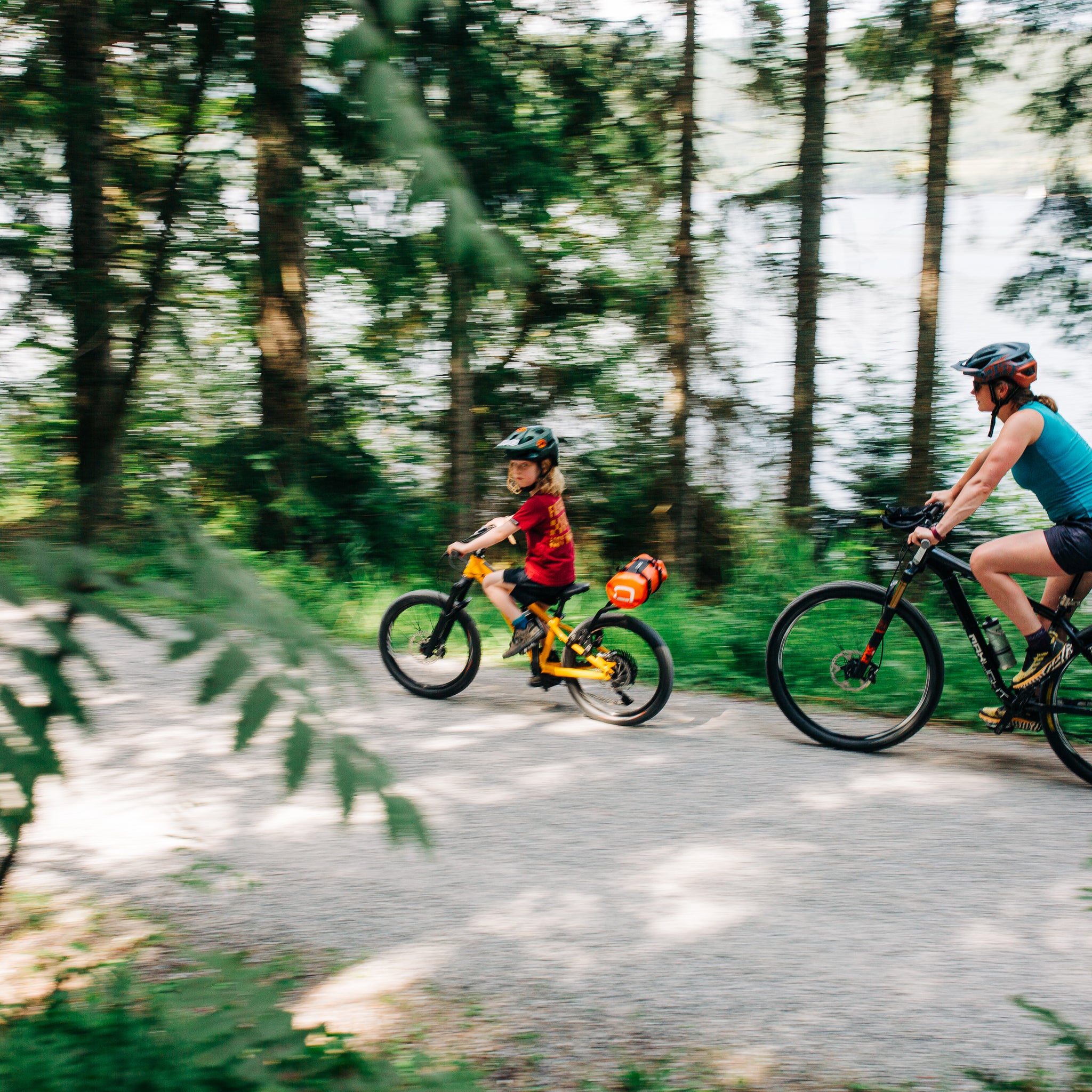 Two people riding bicycles on a forest path with aeroe drybag