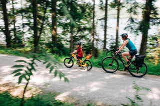 Two people riding bicycles on a forest path with aeroe drybag