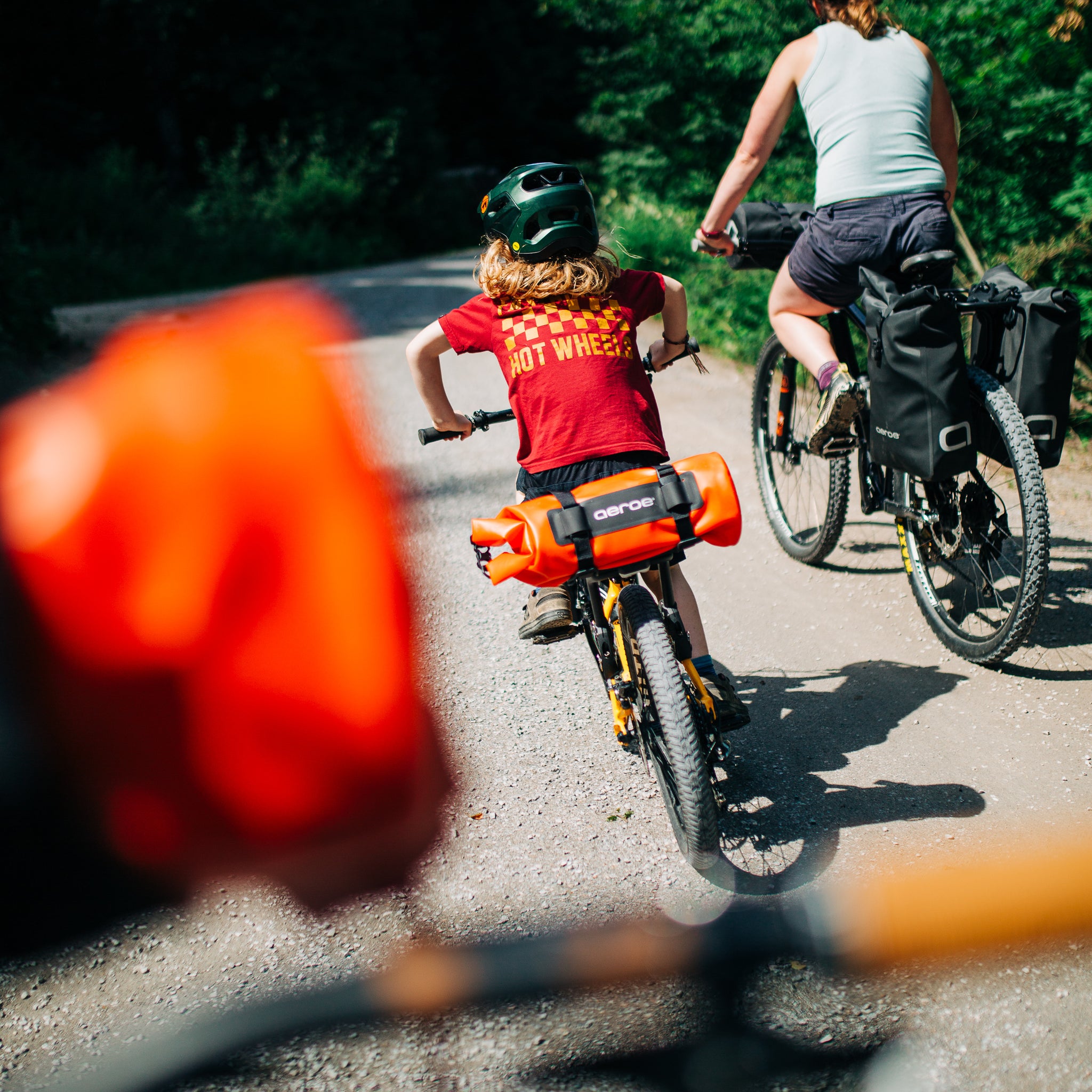 Two people riding bicycles on a road with trees in the background