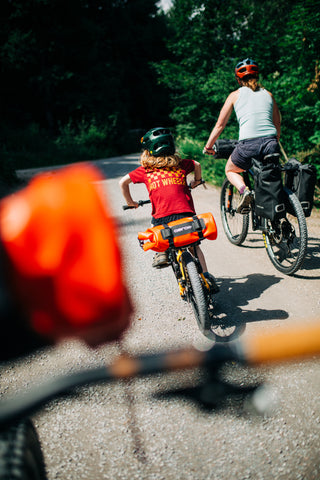 Two people riding bicycles on a road with trees in the background